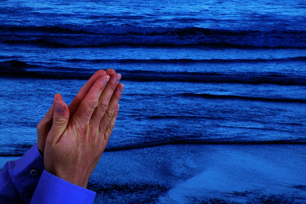 Picture of hands in prayer over water