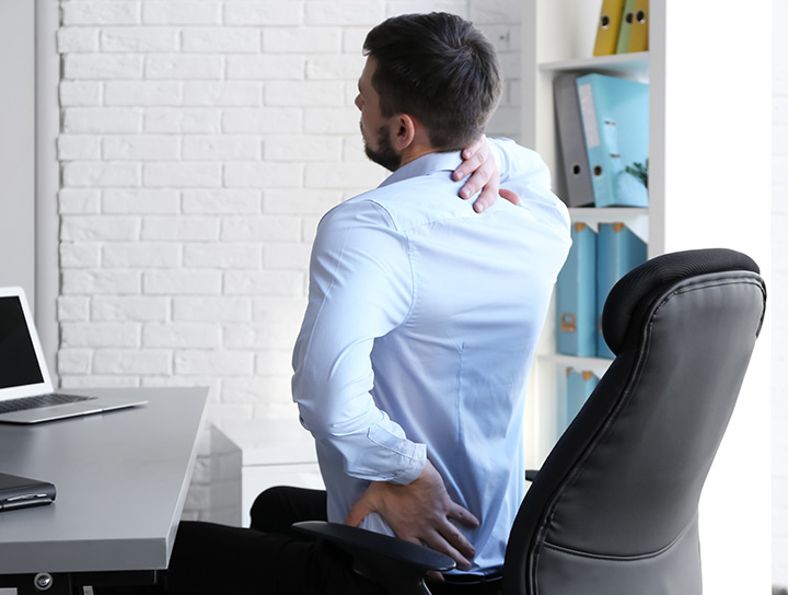 man at desk with a sore neck and shoulders